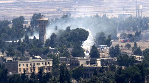 Smoke rises as Syrian rebels allegedly burn buildings they used and detonate their ammunitions before getting on the busses to leave to the northern Syrian city of Idlib from the city of Quneitra by the Syrian-Israeli borders. (AAP)