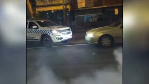 A golden Ford Falcon sedan was caught on camera doing burnouts and spins around a marked police car in the Bendigo area of Victoria. 