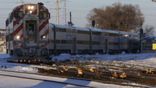A Metra train moves southbound to downtown Chicago as the gas-fired switch heater on the rails keeps the ice and snow off the switches near Metra Western Avenue station in Chicago.