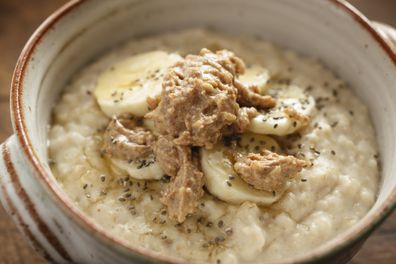 Bowl of Porridge topped with slice banana, chia seeds, honey and peanut butter.