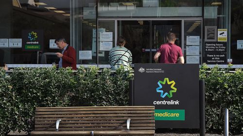 People wait outside a Services Australia outlet