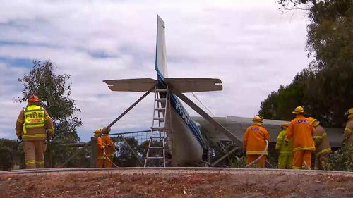 Firefighters working to untangle the plane from the wires it brought down with it.