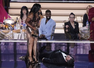 Quinta Brunson, right, winner of the Emmy for outstanding writing for a comedy series for "Abbott Elementary", checks on Jimmy Kimmel as he lays on stage at the 74th Primetime Emmy Awards