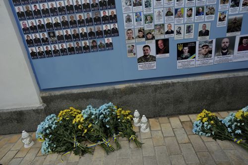 Flowers in the colours of the Ukrainian flag are displayed at the memorial wall outside of St. Michael's Golden-Domed Cathedral in Kyiv, Ukraine, Friday, Feb. 24, 2023.  