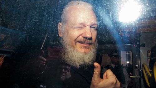 Julian Assange gestures to the media from a police vehicle on his arrival at Westminster Magistrates court on April 11, 2019 in London, England