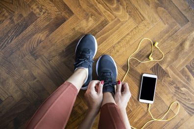 Young woman tying shoelace before workout, getting ready for jogging.