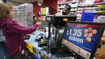 A Mega Millions sign displays the estimated jackpot of $1.35 billion as a customer purchases a Mega Millions ticket at the Cranberry Super Mini Mart in Cranberry, Pa., Thursday, Jan. 12, 2023. 