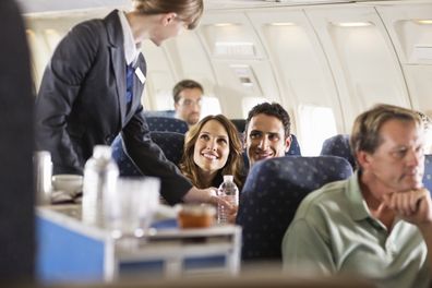 Flight attendant serving customers on an airplane stock photo