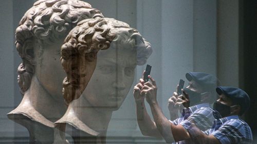 A visitor is reflected in glass as he takes a picture of a replica of the head of Michelangelo's sculpture "David" at the National Museum of Fine Arts Museum.