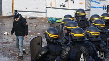 Anti-riot police confront a migrant at the "Jungle" asylum seeker camp in the French city of Calais. (AAP)