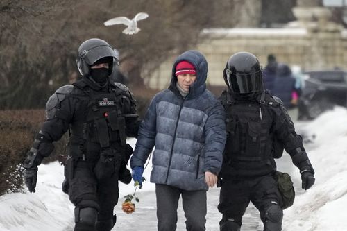 Police detain a man as he wants to lay flowers paying their last respect to Alexei Navalny at the monument, a large boulder from the Solovetsky islands, where the first camp of the Gulag political prison system was established, in St. Petersburg, Russia on Saturday, Feb. 17, 2024