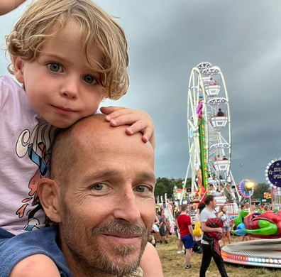 jonnie irwin holding his son on his shoulders at a carnival