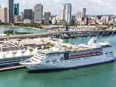 Miami, United States - March 9, 2017:  A large Royal Caribbean cruise-line ship docked at the terminal with downtown Miami, Florida rising in the background.