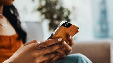 Cropped shot of a woman using a smartphone while relaxing on the sofa at home