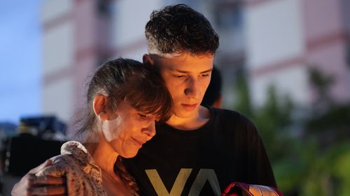 A mother and her son attend a vigil outside the "Cantinho do Bom Pastor" daycare center after a fatal attack on children in Blumenau, Brazil.