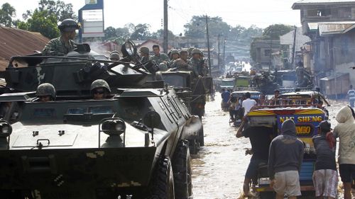 Filipino soldiers on a tanks and military trucks conducting patrol on a flooded community in Jolo, Sulu island, southern Philippines. (AAP)