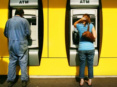 A man and woman withdraw money from a Commonwealth Bank ATM