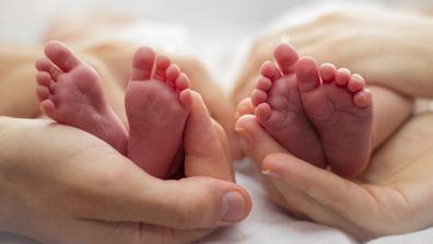 Twins. Twins feet. Mother and twins. Birth. Baby feet