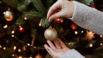 A woman decorating a Christmas tree with baubles