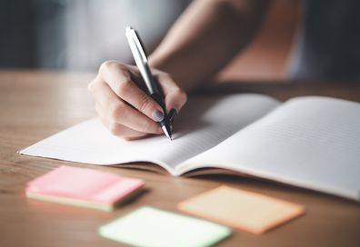 Woman writing in a notebook with a pen