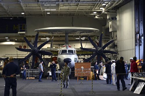 Crew members walk by aircraft in the hanger of the Theodore Roosevelt (CVN 71), a nuclear-powered aircraft carrier, anchored in Busan Naval Base in Busan, South Korea Saturday, June 22, 2024.