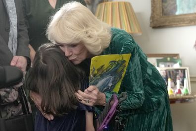 Queen Camilla hugs a child after she invited children, supported by Helen & Douglas House and Roald Dahl's Marvellous Children's Charity, to decorate a Christmas tree and receive a few festive surprises at Clarence House in London, Wednesday, Dec. 6, 2023. 