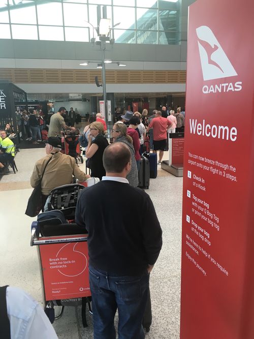 Customers wait for check-in terminals to come back to life after a power outage. Image: Max Roberts