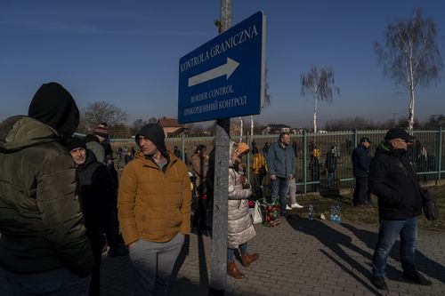 People wait for family members to arrive from Ukraine at the Medyka border crossing, in Medyka, Poland, Saturday, Feb. 26, 2022. The U.N. refugee agency said Saturday that nearly 120,000 people have so far fled into neighboring countries and that number is going up fast. (AP Photo/Bernat Armangue)