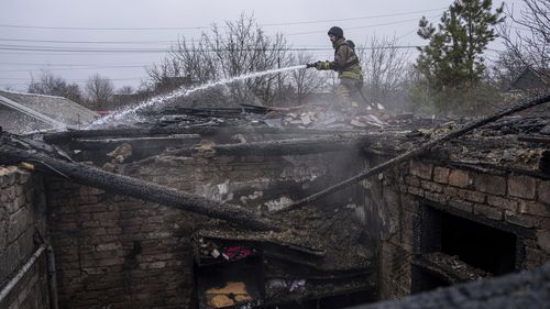 A rescue worker puts out the fire of a house which was destroyed by Russian shelling in Kostiantynivka, Ukraine, Wednesday, March 8, 2023. (AP Photo/Evgeniy Maloletka)