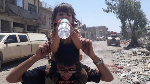 A little girl takes a drink of water in Mosul. (Owen Holdaway)