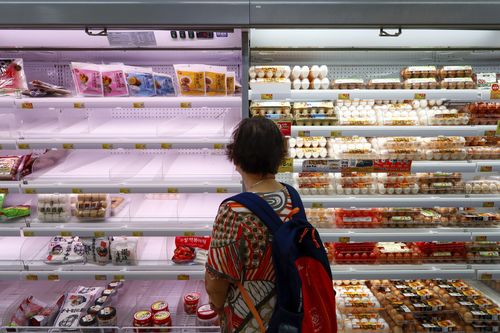 A shopper looks at  near empty shelves at a supermarket as super typhoon Saola approaches Hong Kong on Friday, Sept. 1, 2023.  