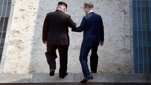 North Korean leader Kim Jong Un, left, and South Korean President Moon Jae-in cross the military demarcation line at the border village of Panmunjom. (AAP)