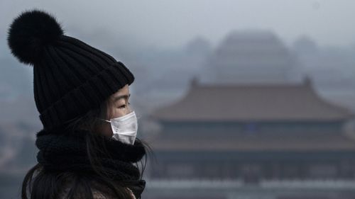 A Chinese girl wears a protective mask as she stands on an overlook towards the Forbidden City, which was closed by authorities, during the Chinese New Year holiday on January 26, 2020 in Beijing, China.