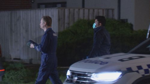 Two police officers walking past a police car at night.