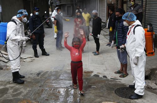 A young Nepalese girl is sprayed with disinfectants as she arrives to get free food distributed by social workers during lockdown to control the spread of the new coronavirus in Kathmandu, Nepal