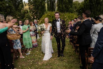 Wedding couple, Matt and Regina, walking amongst friends who are throwing confetti. 