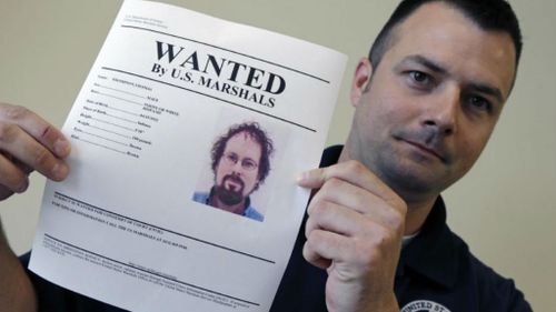 A US official holds up a print-out of Thomas Thompson's arrest warrant (AP).