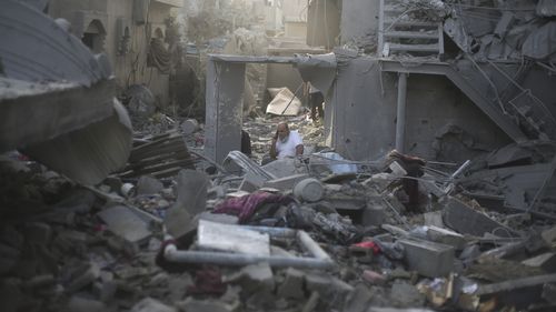 A Palestinian talks on the phone in the buildings destroyed in the Israeli bombardment