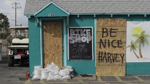 A sign reading "Be Nice Harvey" was left behind on a boarded up business, (AAP)