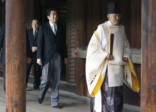 Then Japanese Prime Minister Shinzo Abe, second from right, follows a Shinto priest to pay respect for the war dead at Yasukuni Shrine in Tokyo on Dec. 26, 2013