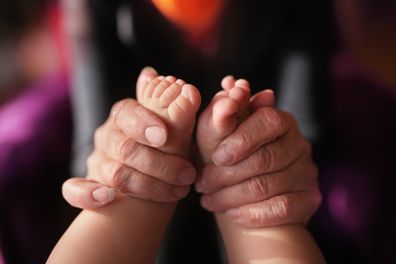 Grandmother holding baby feet