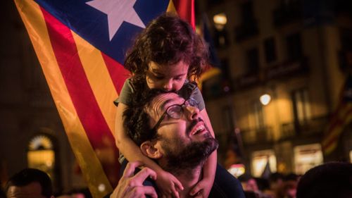 A child rests on a man's shoulders with a "estelada" or pro independence flag in the background. (AP)