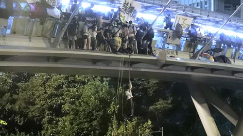 Protesters use a rope to lower themselves from a pedestrian bridge to waiting motorbikes in order to escape from Hong Kong Polytechnic University and the police in Hong Kong.