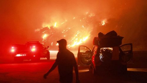 A resident walks by his car packed with belongings as Highway 330 is engulfed by the Line Fire near Running Springs, California, on September 7.
