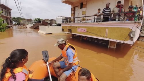 People stranded in flood waters watch others being rescued at Kolhapur in western Maharashtra state, India.