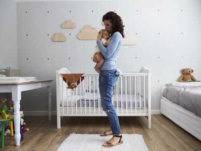 Mother Comforting Newborn Baby Son In Nursery