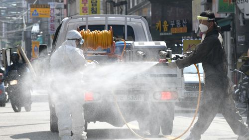 A health official wearing protective gear sprays disinfectant on the street near the Sarang Jeil Church, a new coronavirus infection cluster, in Seoul on August 18, 2020. 