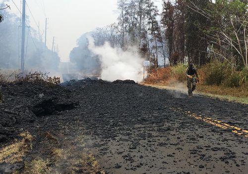 First Lt. Aaron Hew Len, of the U.S. National Guard, tests air quality near cracks that are emitting toxic gasses from a lava flow in the Leilani Estates subdivision near Pahoa, Hawaii, Tuesday, May 8, 2018. Scientists confirm that volcanic activity has paused at all 12 fissures that opened up in a Hawaii community and oozed lava that burned 35 structures. Officials warn that hazardous fumes continue to be released from the cracks in the ground. (AP Photo/Caleb Jones)