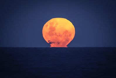 A Strawberry Moon rises over the ocean on Narrawallee Beach, located near Mollymook on the South Coast of New South Wales in Australia, May 6, 2020.