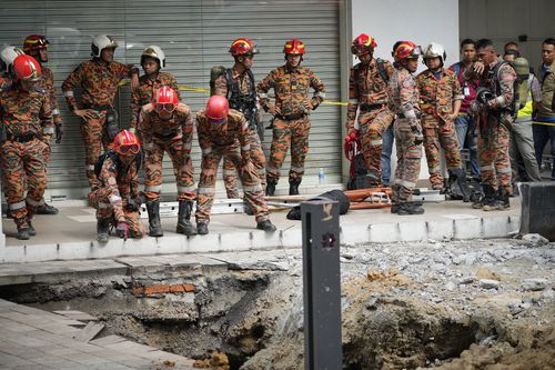 Fire and Rescue Service investigate after receiving reports that a woman fell into a sinkhole after a section of pavement collapsed in Kuala Lumpur, Friday, August 23, 2024. 